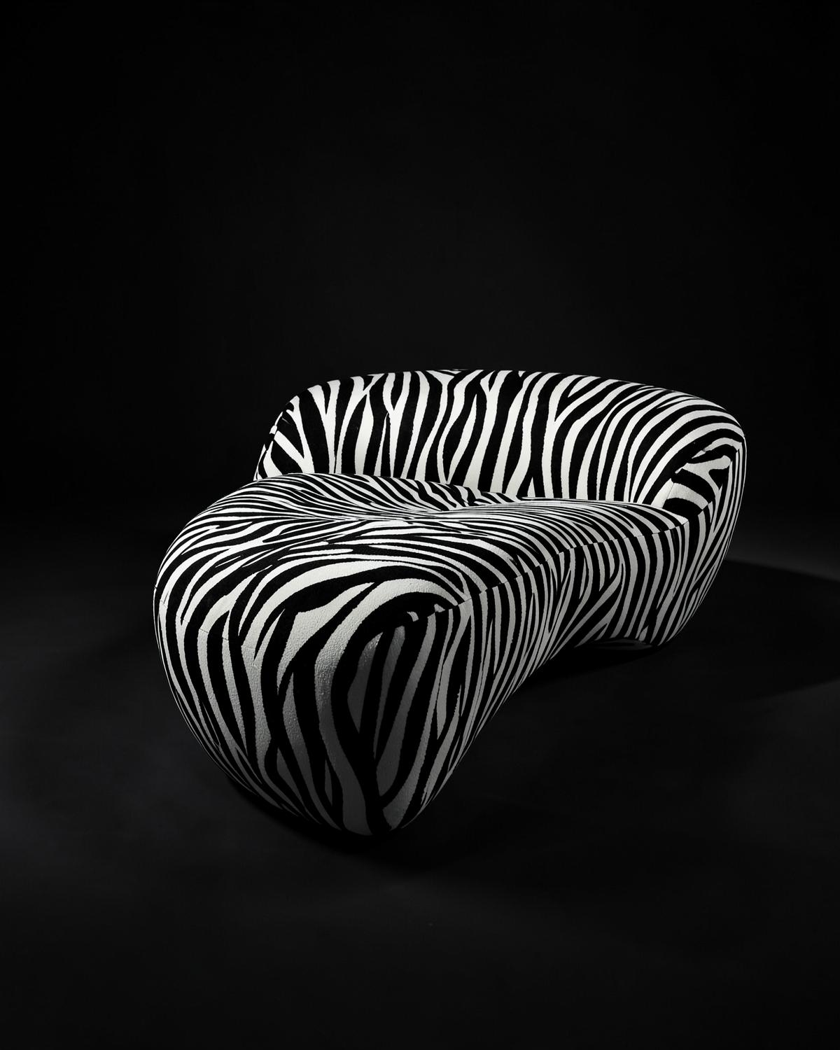 Curved sofa upholstered in bold black and white zebra stripes